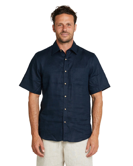 A male model posing and wearing the Okanui Linen Short Sleeve shirt in navy.