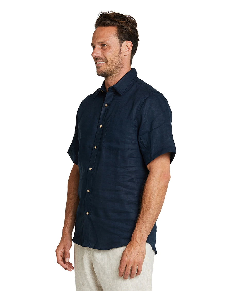 A side view of a male model wearing the Okanui Linen Short Sleeve shirt in navy.