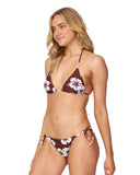 A woman wearing a hibiscus sienna swim pant with a tie-side design and a bikini top showing the side details.
