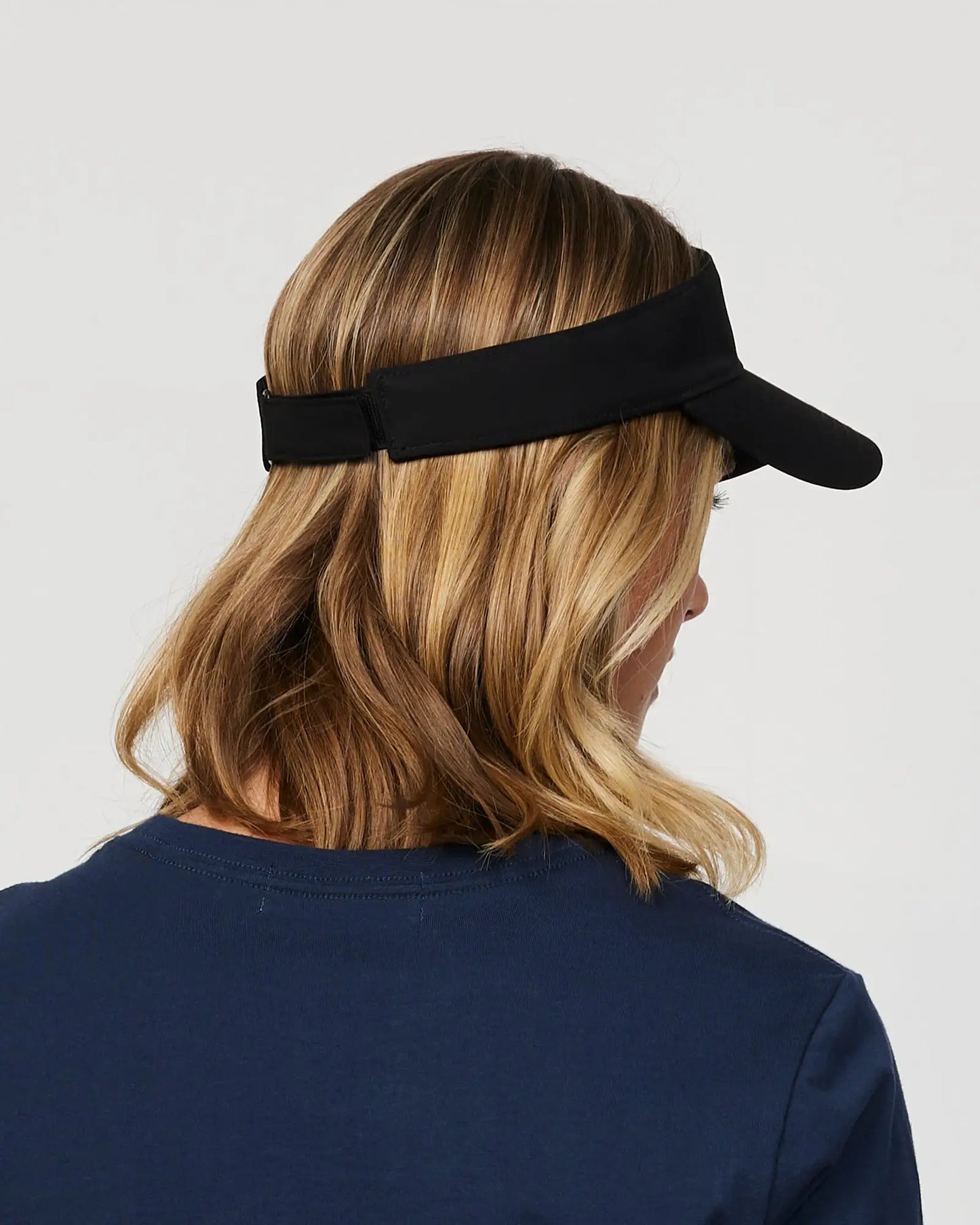 Back-Right view of a female model wearing the Okanui Ikon Visor Cap in Black