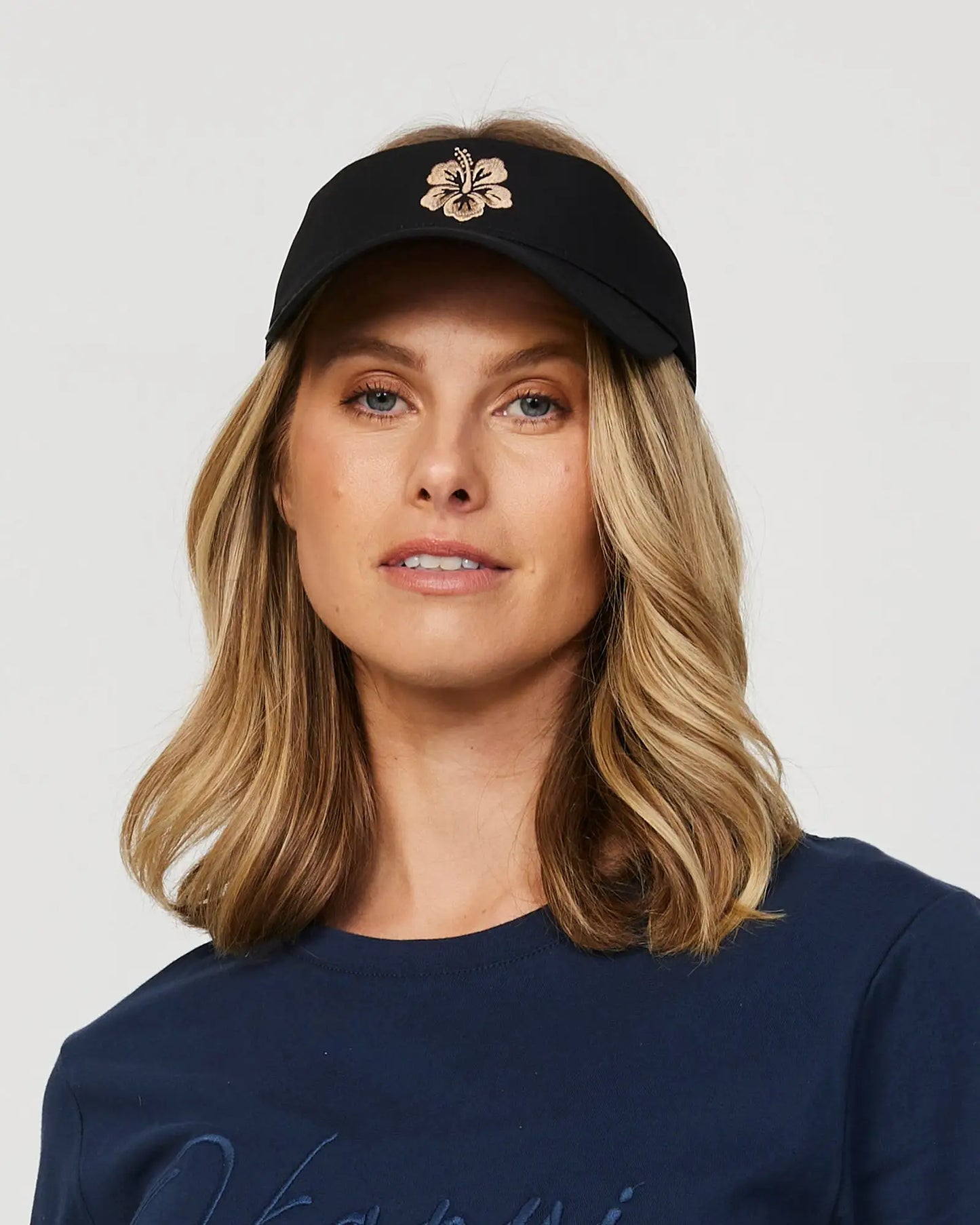 Front view of a female model wearing the Okanui Ikon Visor Cap in Black