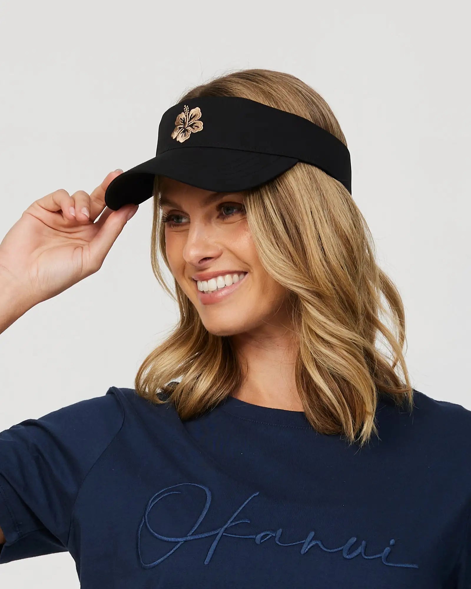 Left view of a female model wearing the Okanui Ikon Visor Cap in Black