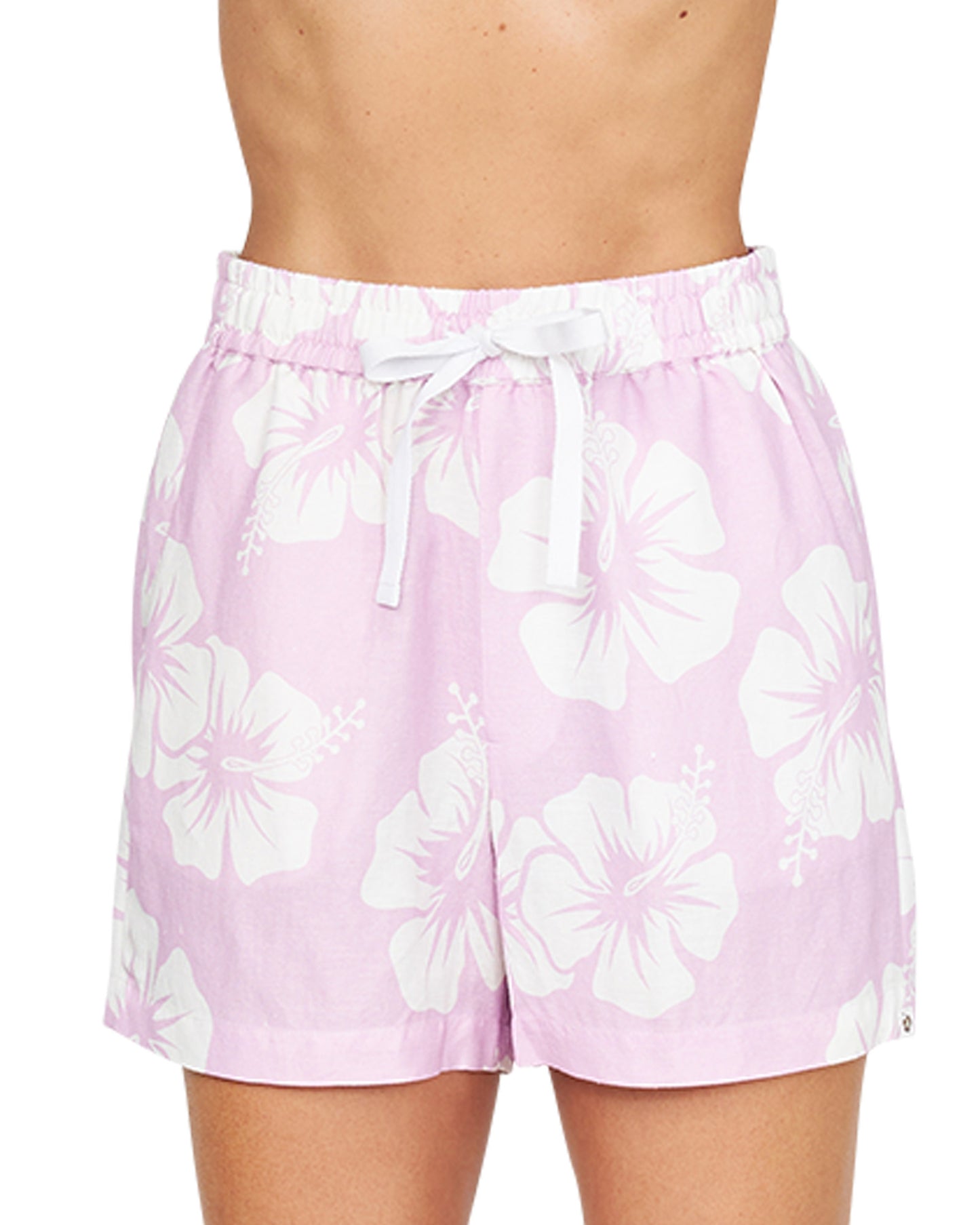 A close up front lower view of a female model wearing the Okanui OG Paradise Beach Short in Hibiscus Pale Pink.