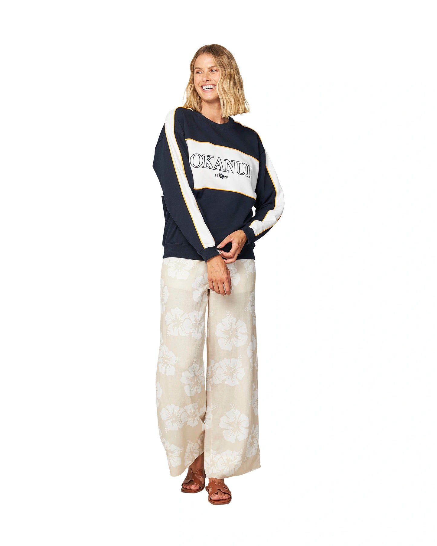 Women's white and navy blue sweater paired with pants decorated with hibiscus flowers.