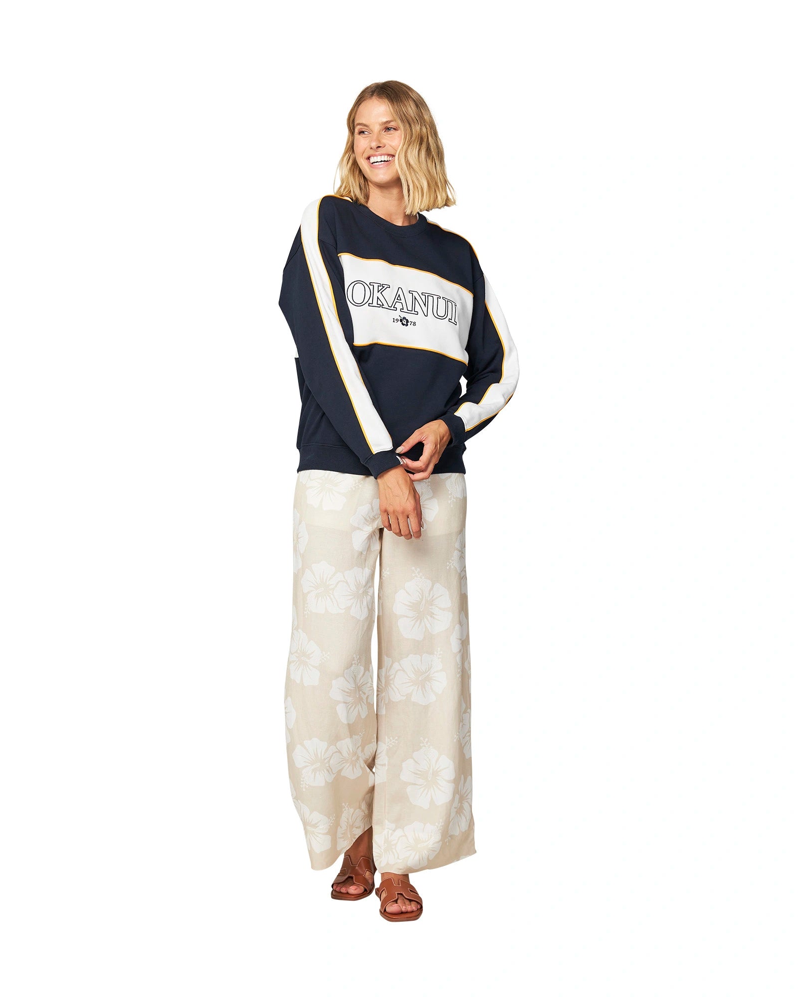 Women's white and navy blue sweater paired with pants decorated with hibiscus flowers.