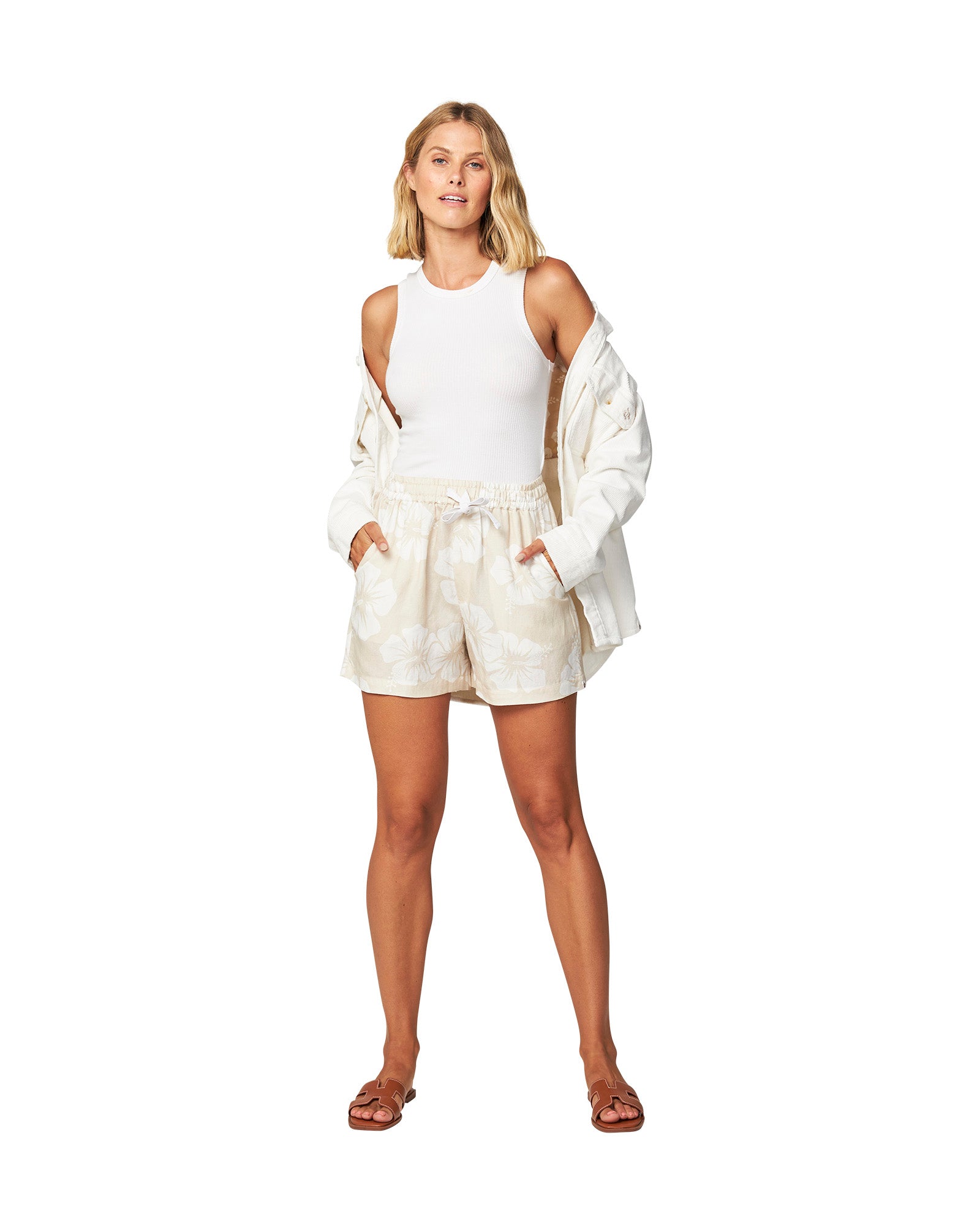 Full body of a female model wearing a jacket paired with the Okanui OG Paradise beach linen swim shorts in Hibiscus Natural color