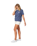 One leg in front pose of a female model wearing the Okanui Ikon cotton T-shirt in Washed Navy color
