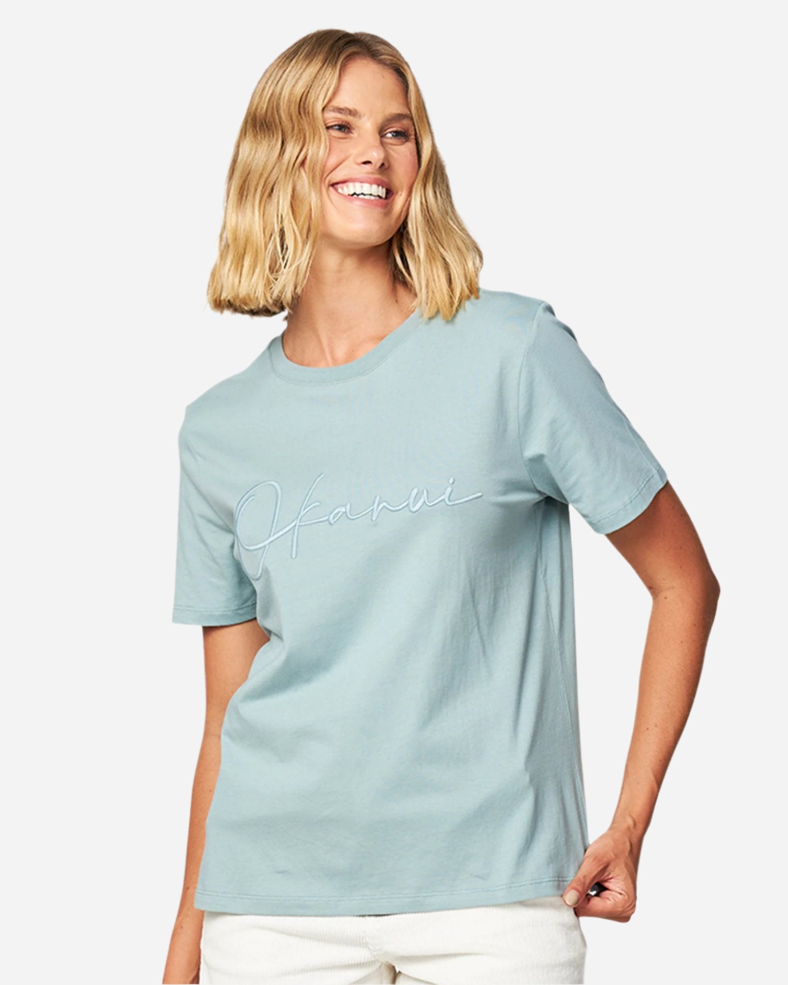 Front view of a female model wearing the Okanui Signature short sleeves T-shirt in Sage color