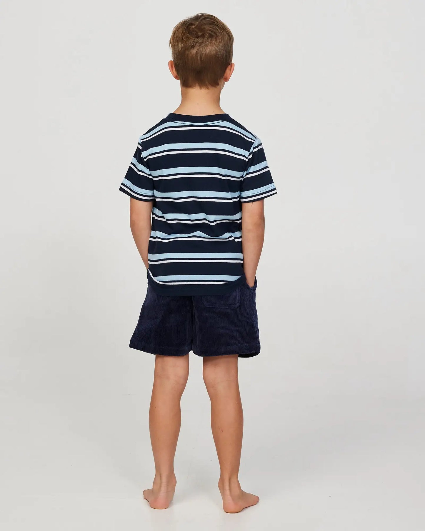 Full body back view of a little boy model wearing the Okanui Corduroy Walk Short in Iron Navy