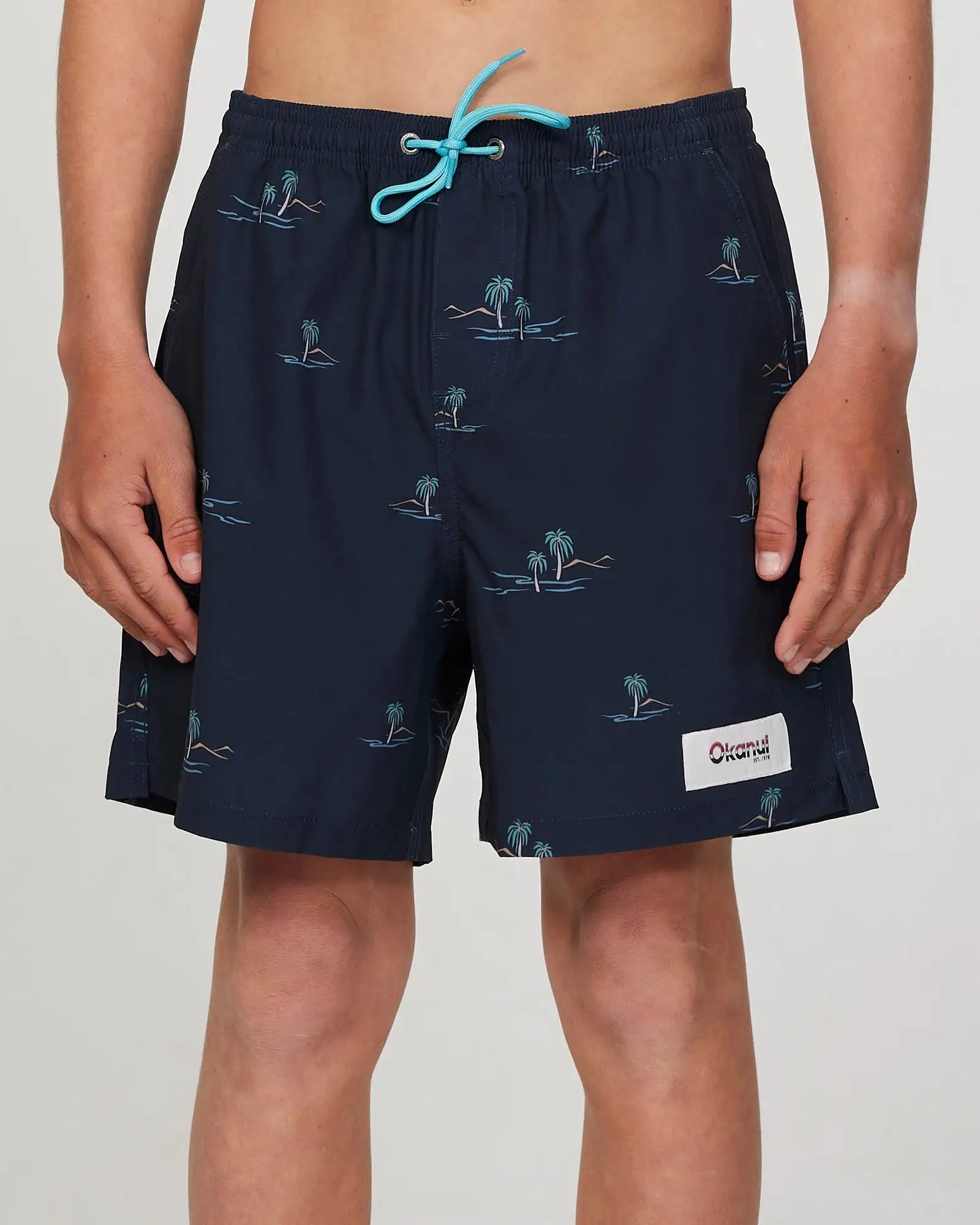 Front view of a boy model wearing the Okanui Isle stretch swim short for boys in Black