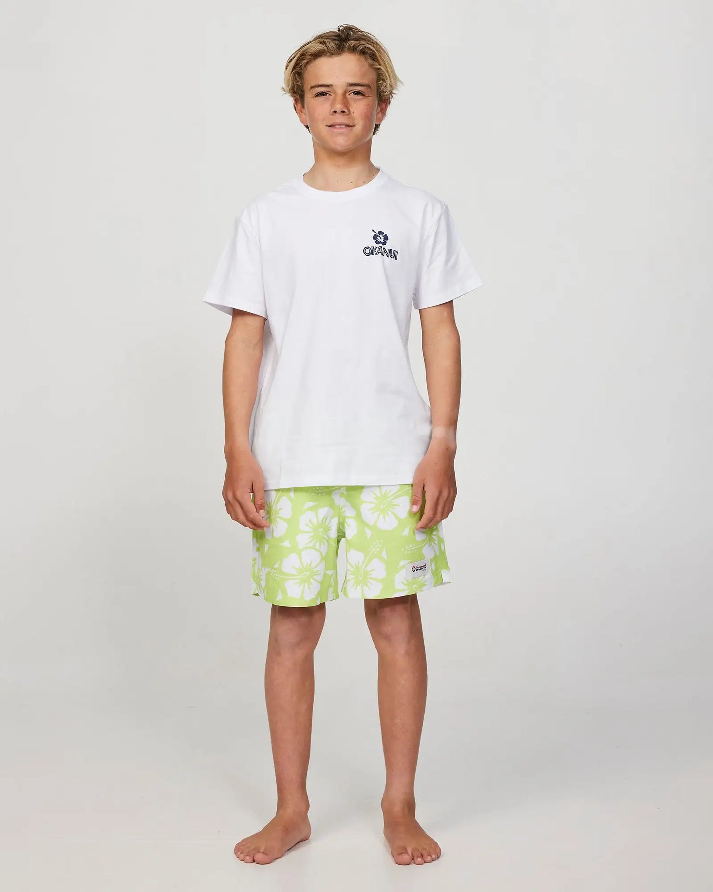 Full body front view of a boy model wearing the Okanui Riptide T-shirt for boys in White