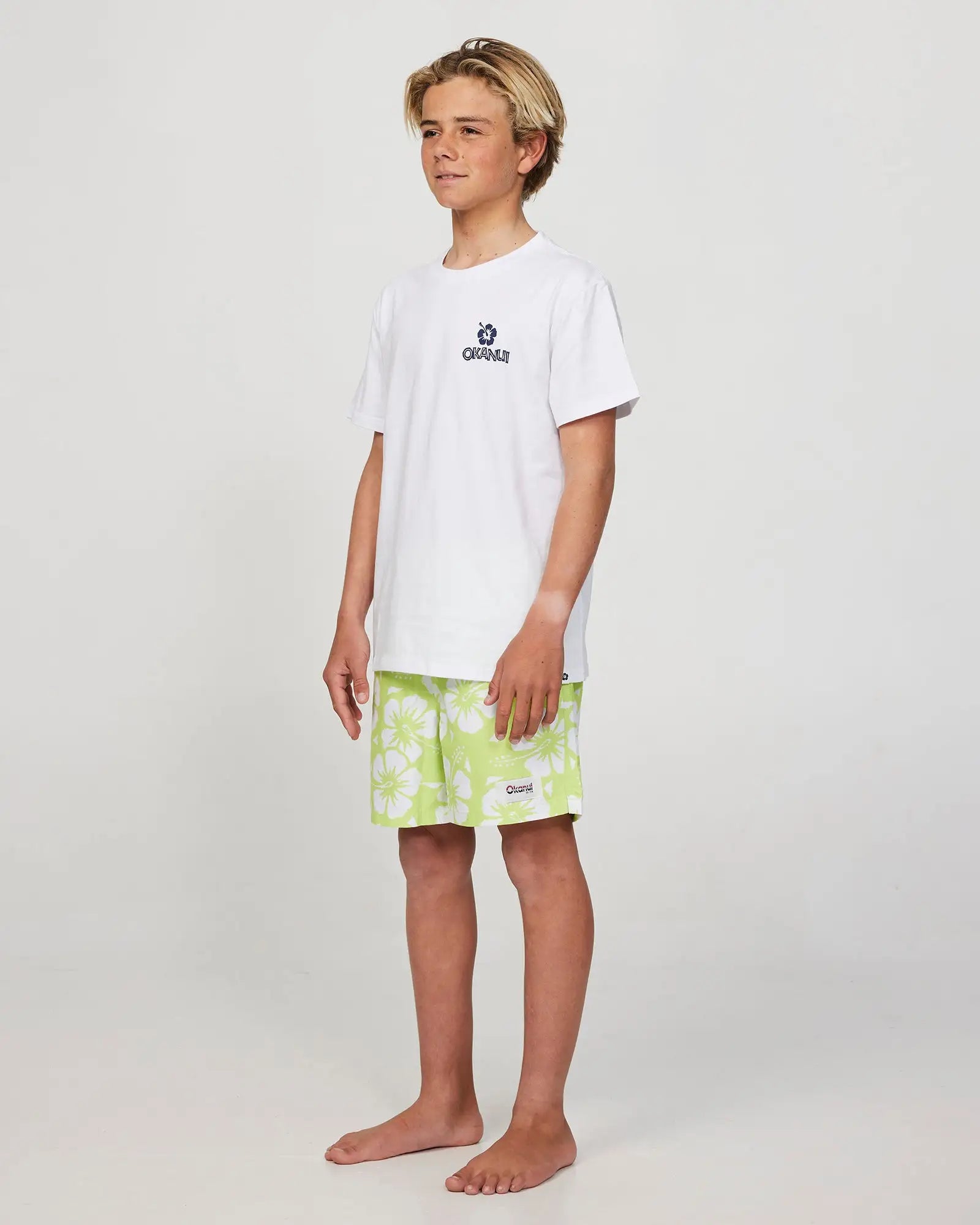 Front-left view of a boy model wearing the Okanui Riptide T-shirt for boys in White