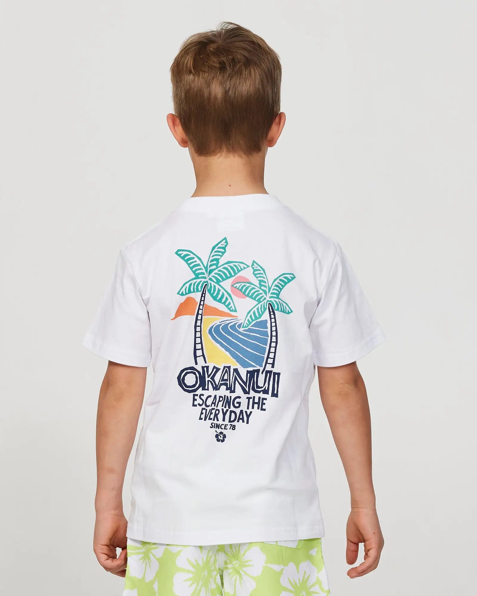 Closeup back view of a little boy model wearing the Okanui Riptide T-shirt for boys in White