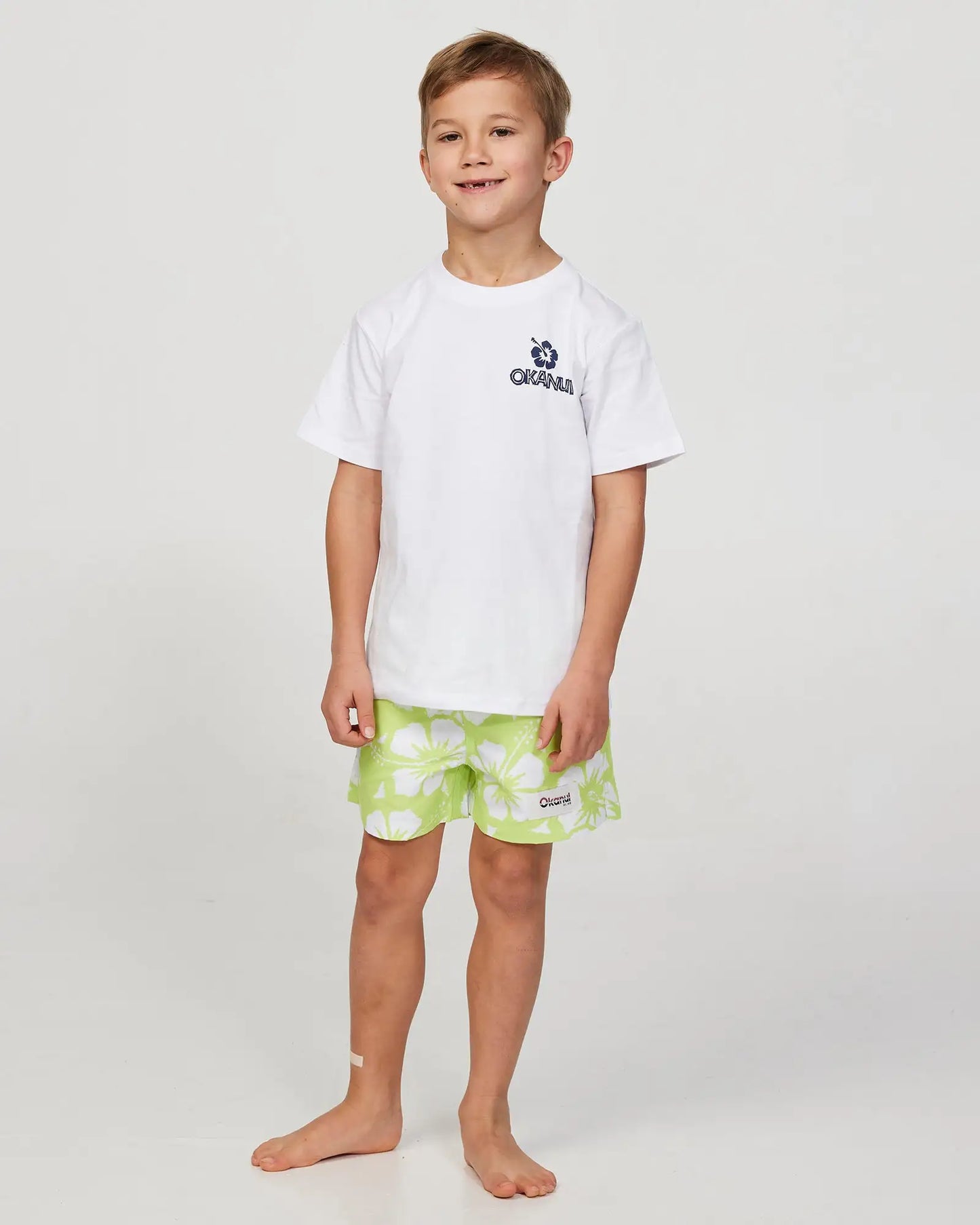 Full body front view of a little boy model wearing the Okanui Riptide T-shirt for boys in White