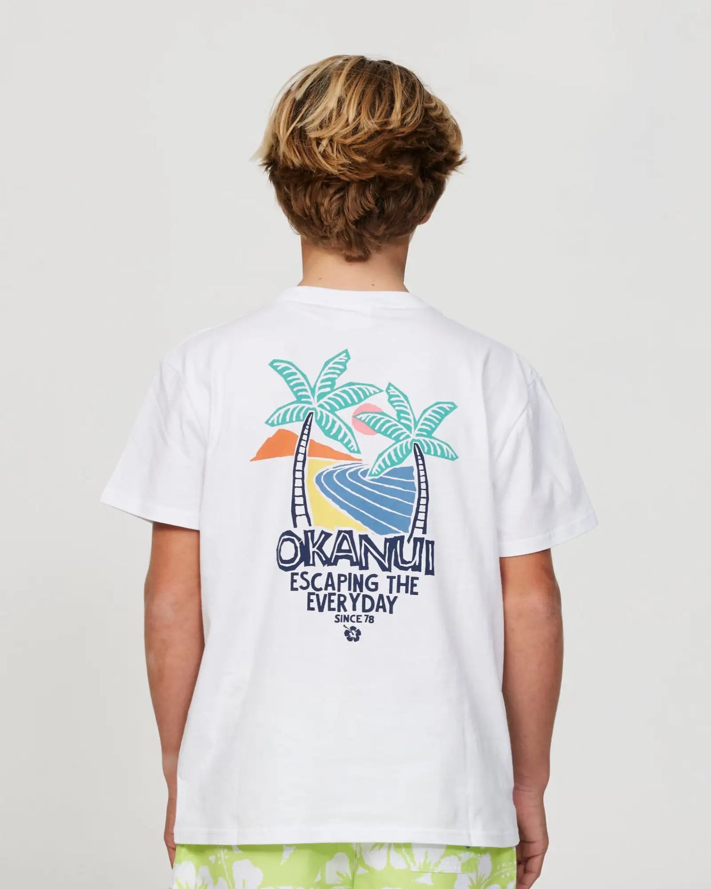 Closeup back view of a boy model wearing the Okanui Riptide T-shirt for boys in White