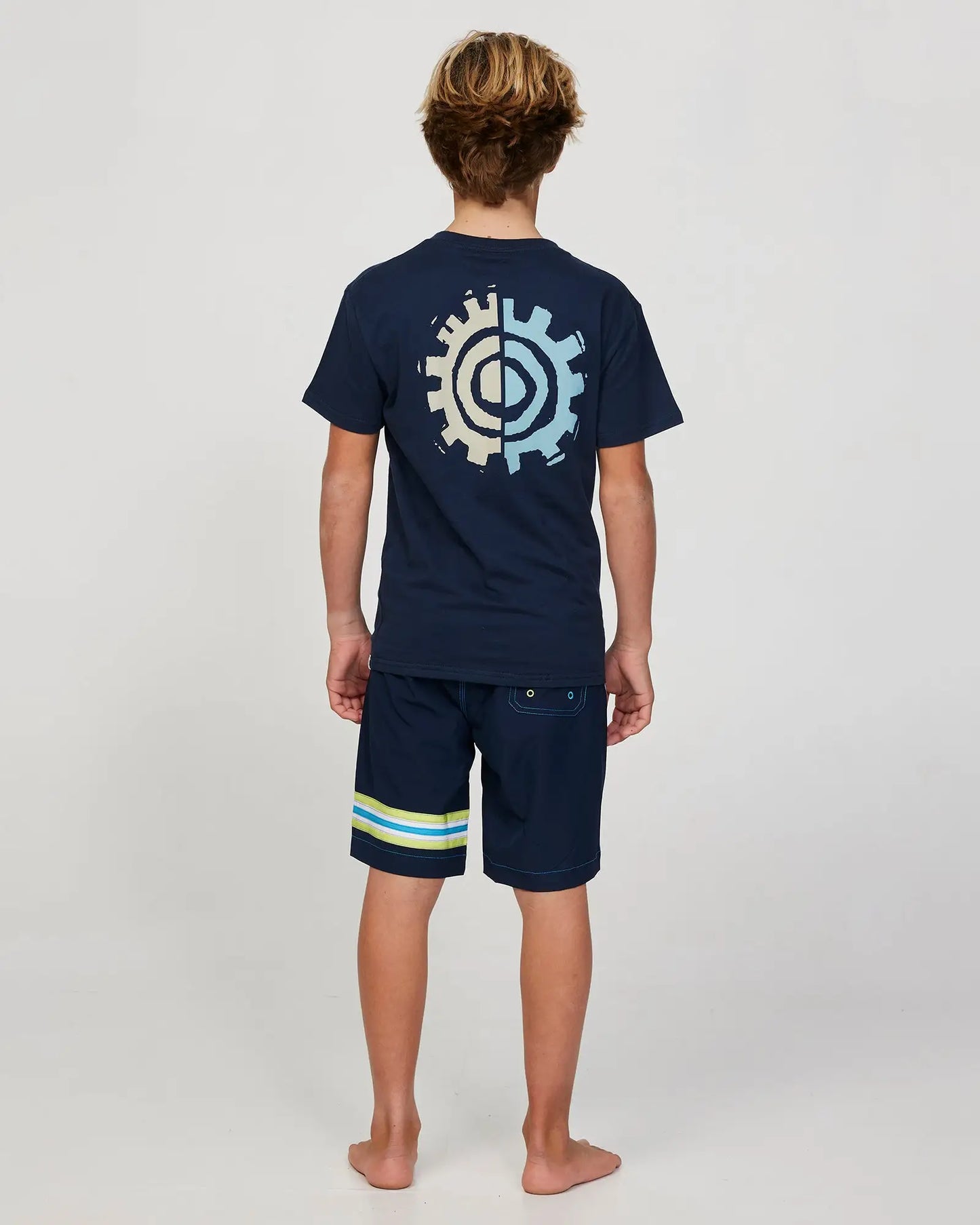 Full body back view of a boy model wearing the Okanui Twin Flame T-shirt for boys in Navy