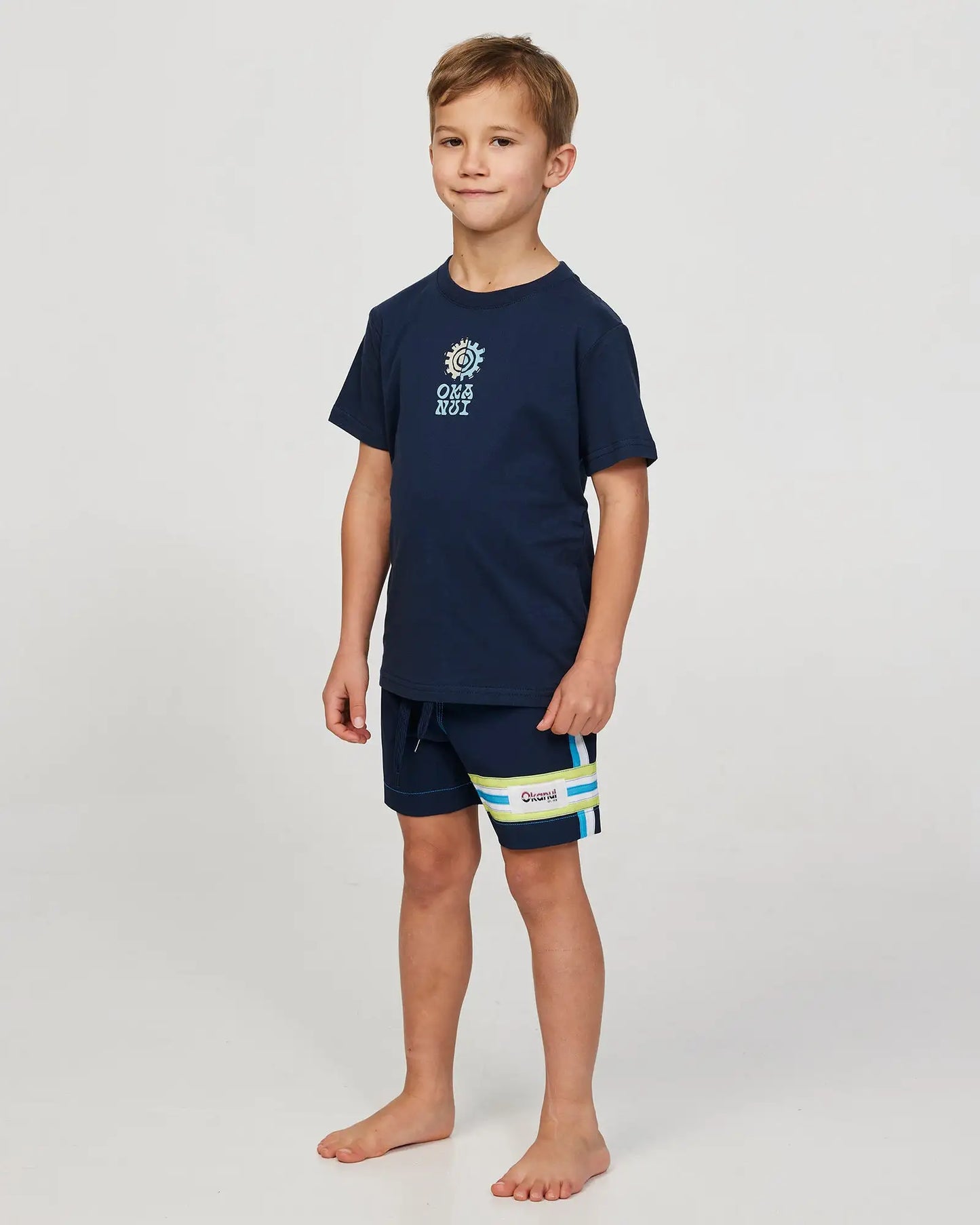 Full body front view of a little boy model wearing the Okanui Twin Flame T-shirt for boys in Navy