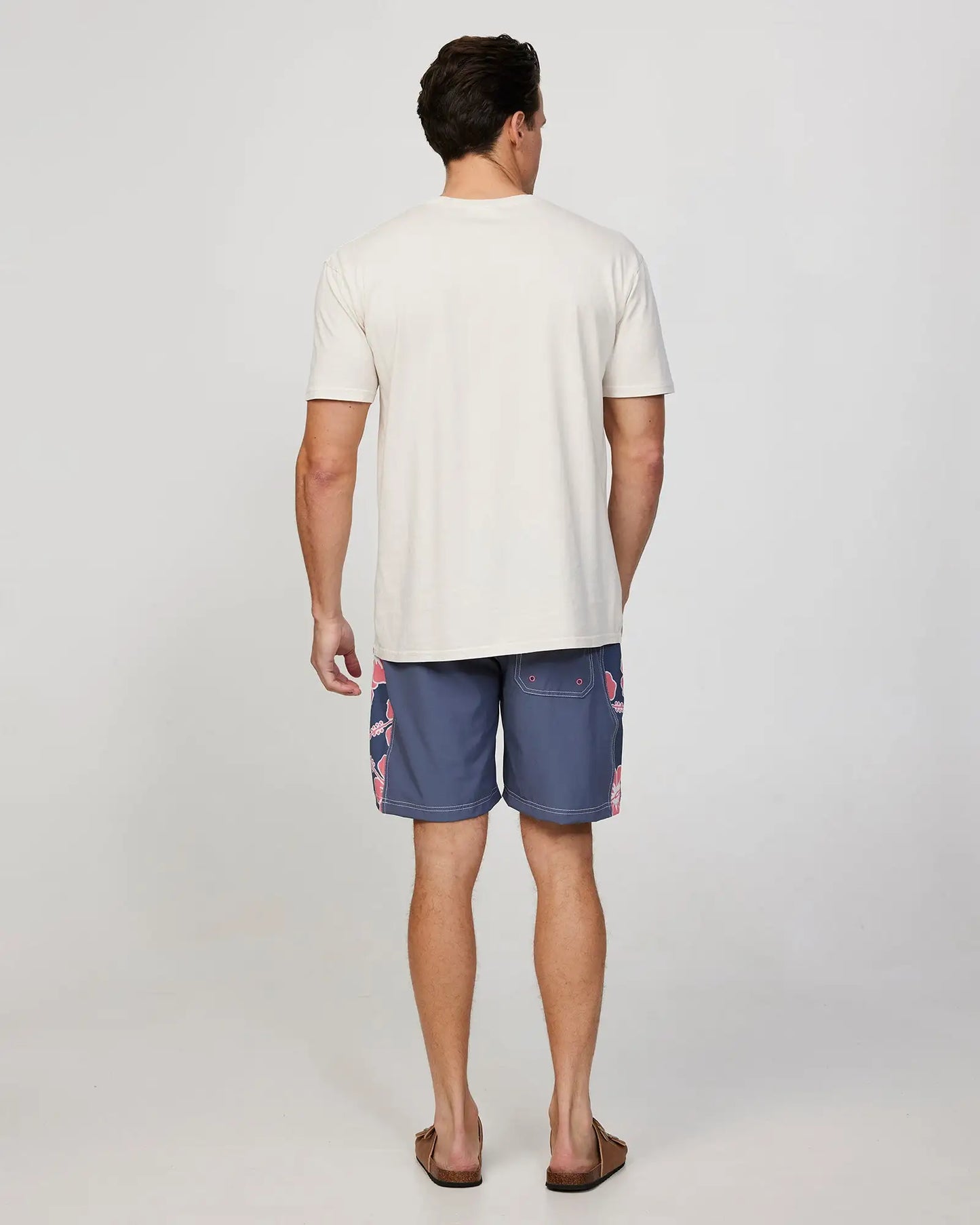 Full body back view of a male model wearing the Okanui Mens Way-Back-When boardrider board short in Iron Pink