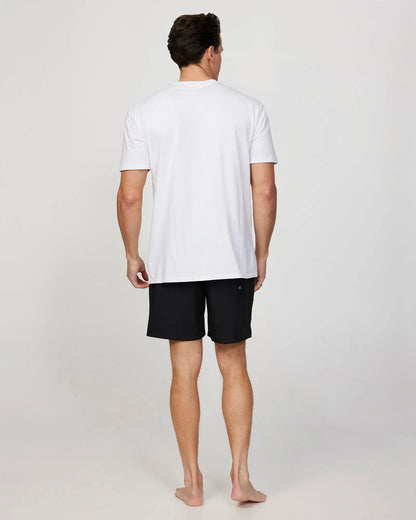 Full body back view of a male model wearing the Okanui Mens Onboard stretch swim short in Black paired with a white shirt