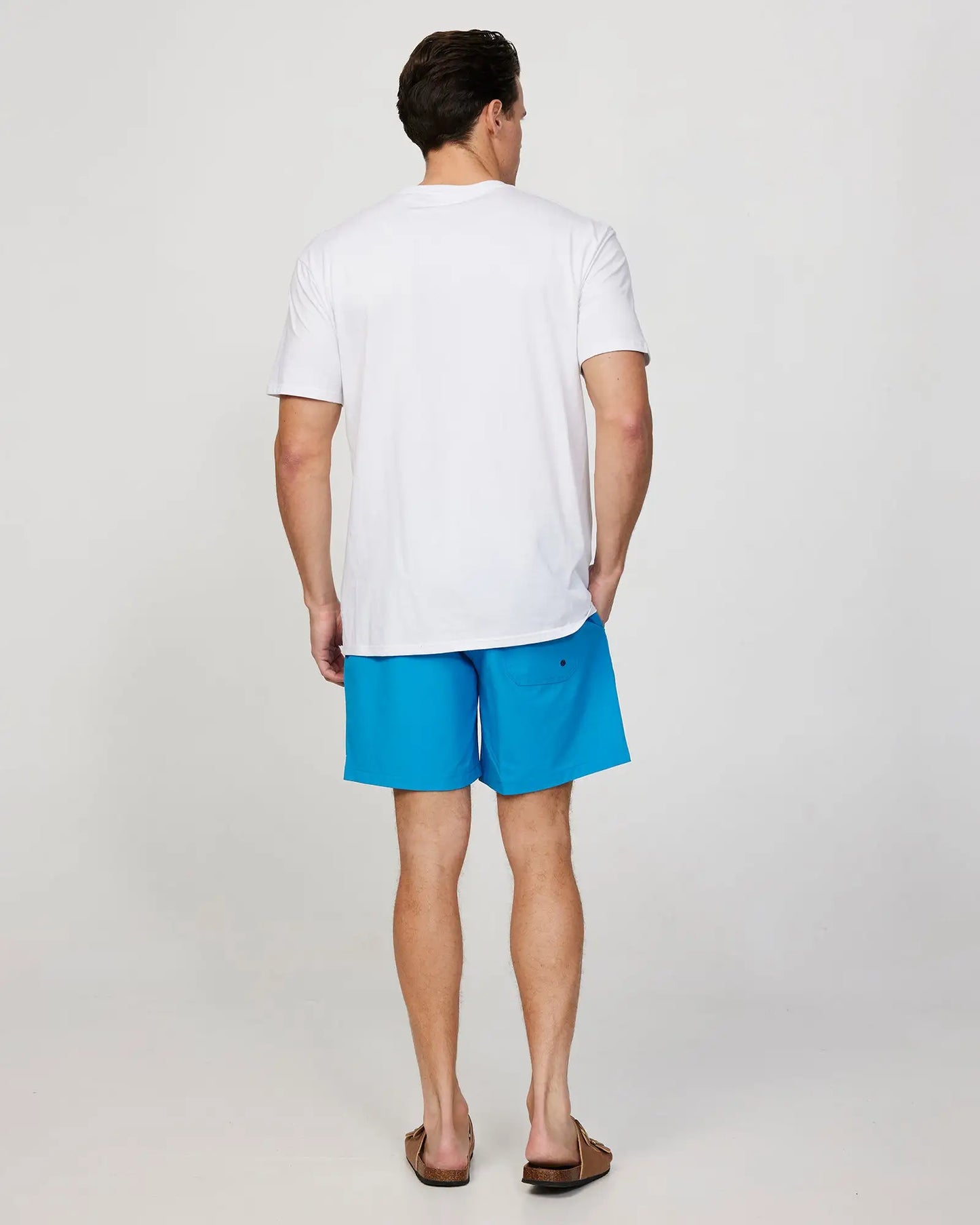 Full body back view of a male model wearing the Okanui Mens Onboard stretch swim short in Blue