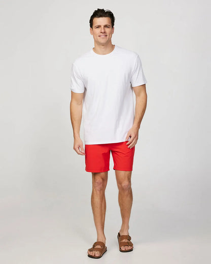 Full body front view of a male model wearing the Okanui Mens Onboard stretch swim short in Red paired wit a white shirt