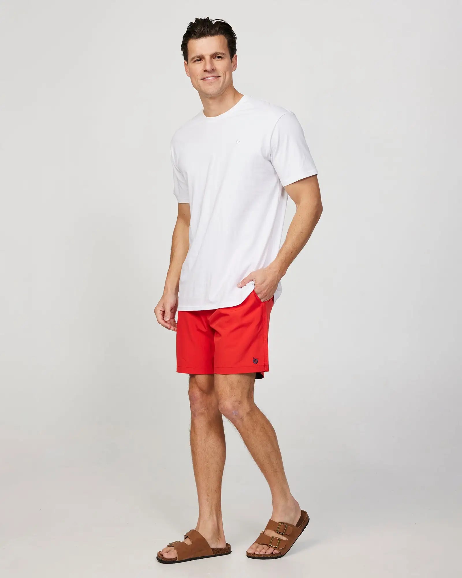 Full body left side view of a male model wearing the Okanui Mens Onboard stretch swim short in Red