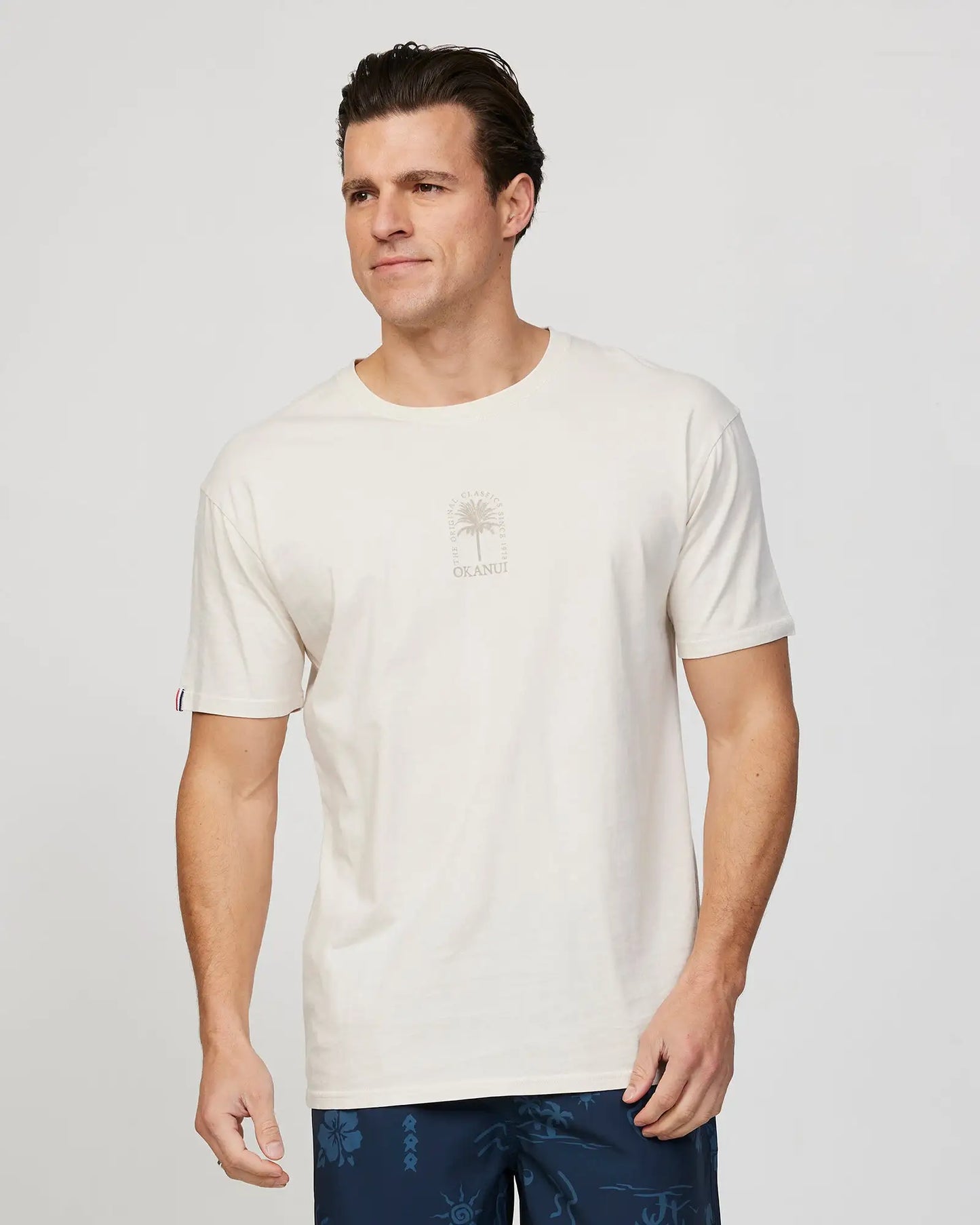 Front view of a male model wearing the Okanui Mens Barrel Tee T-shirt in Stone