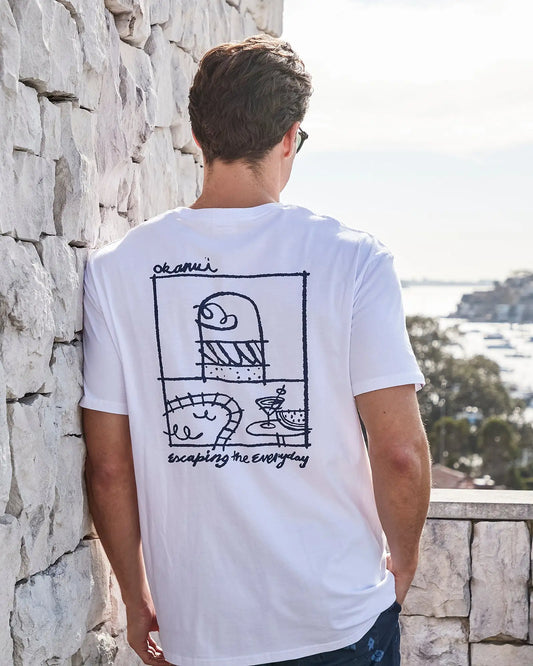 Back view of a male model leaning on the wall wearing the Okanui Cruise Tee T-shirt in White