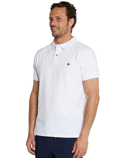 Half body pose of a male model wearing navy shorts and the Okanui Classic Polo Shirt in white.