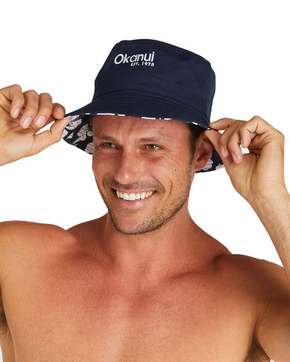 The Okanui Reversible Bucket hat being worn by a smiling male model.