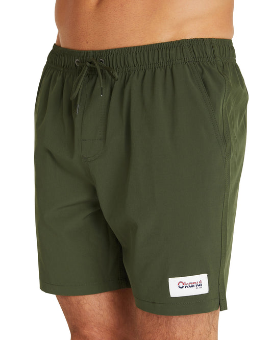 A close up view of the Okanui Plain Stretch Swim Shorts in Plain Khaki color showcasing the Okanui patch on the lower left part of the shorts.